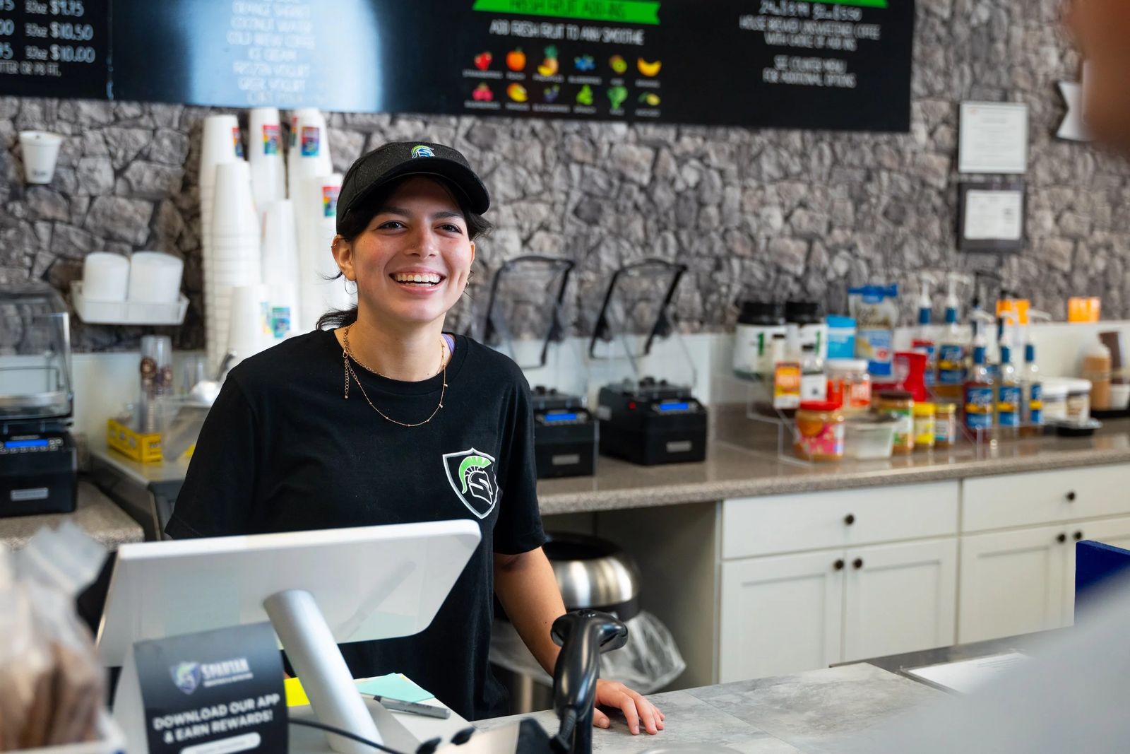 A smiling Spartan Smoothies team member at the register