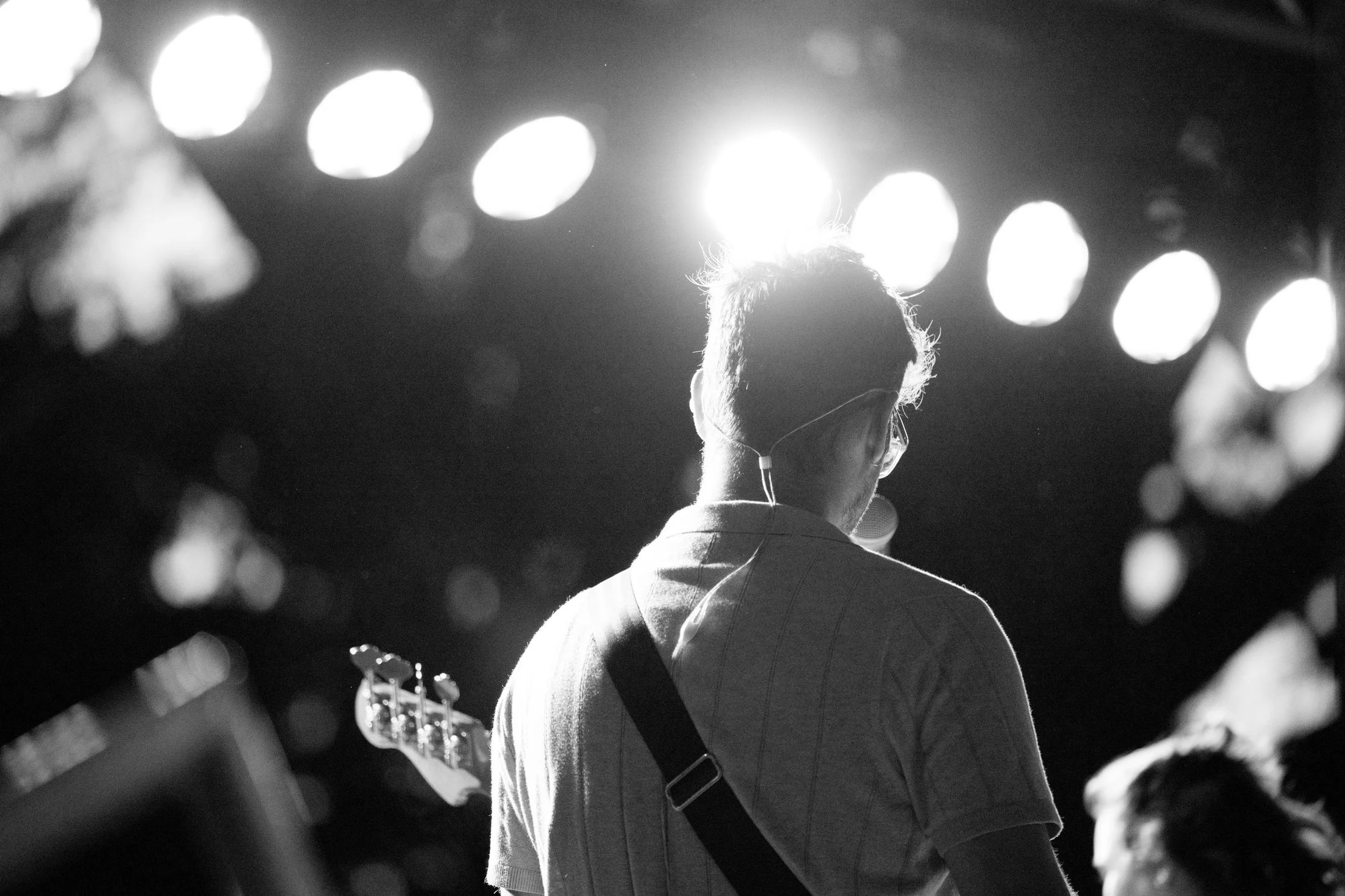 A guitarist under stage lights, in black and white