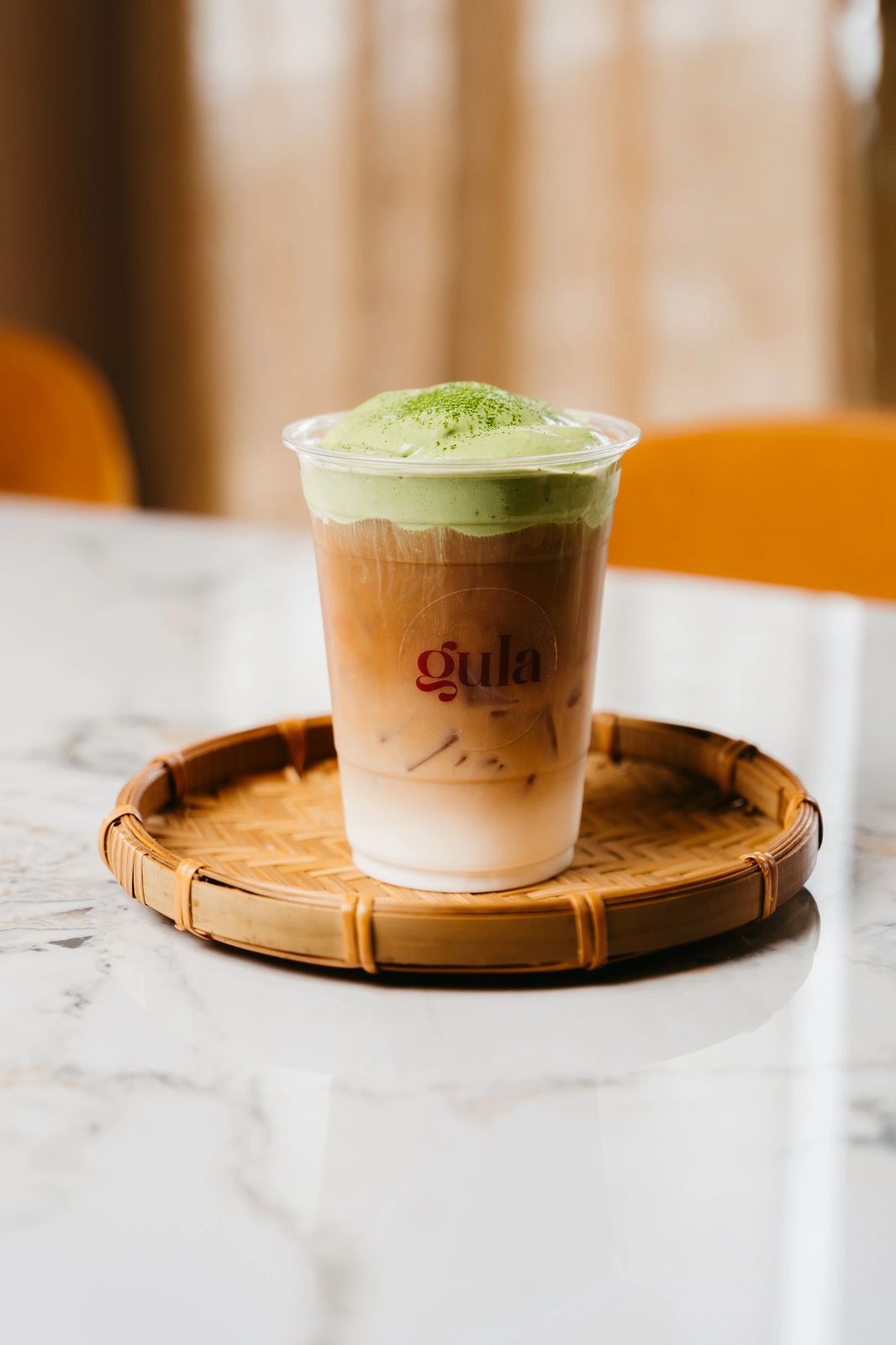 A layered Gula drink on a wooden tray